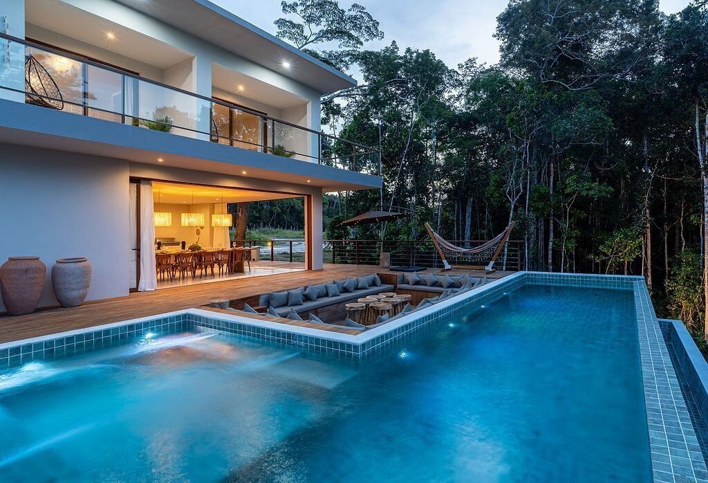 A modern house with a swimming pool, outdoor seating, and a hammock.