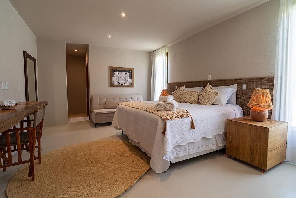 A bedroom with a bed, bedside tables, a chair, a rug, and a painting on the wall.