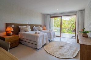 Quarto de hotel com duas camas, uma janela grande, varanda e um tapete tecido.