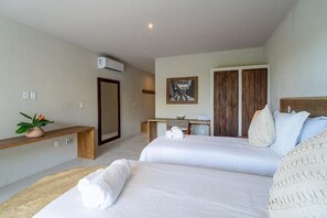 Ein Hotelzimmer mit zwei Betten, einem Schreibtisch, einem Spiegel und einer Wandklimaanlage.