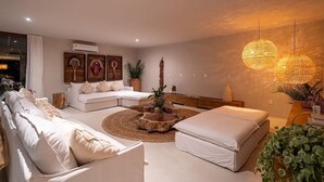 A modern living room with a sectional sofa, a round coffee table, and a large window. - 159M- Casa de Luxo em Trancoso-BA  (Porto Seguro)