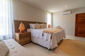 Ein Schlafzimmer mit einem Bett, Nachttischen, einer hölzernen Kommode und einem großen Fenster.