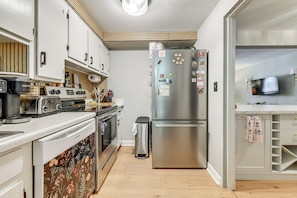 A modern kitchen with a stainless steel refrigerator, a dishwasher, a toaster, and a microwave. - Walk to Village District! Charming Escape w/ Yard (Raleigh)