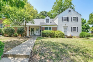 A two-story house with a front porch, a small attached garage, and a well-maintained lawn. - Walk to Village District! Charming Escape w/ Yard (Raleigh)