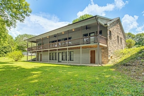 Ein zweistöckiges Haus mit Balkon, großen Fenstern und einer Steinfassade.