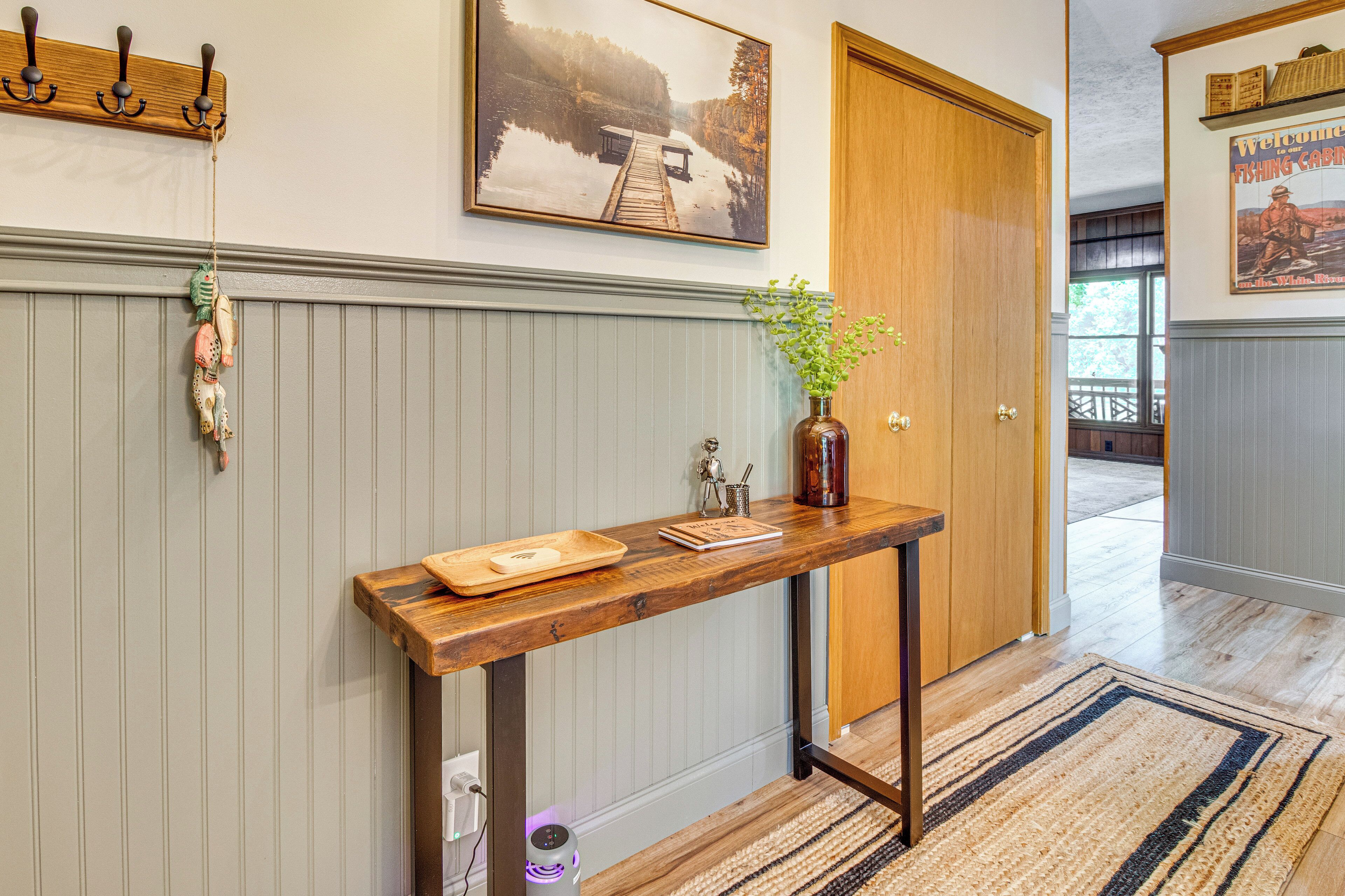 A hallway with a wooden console table, a welcome sign, and a framed picture on the wall.