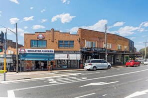 Straßenansicht, ein Gebäude mit einem Broaster Chicken Restaurant und einem Fresh Tama Sushi Lokal.