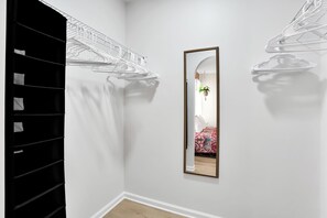 A hallway with a mirror, a black shelving unit, and a bed with a patterned bedspread. - Walk to Oak Island Beach! Casablanca Estate (Oak Island)