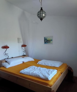 Ein Einzelbett mit zwei Kissen, ein Nachttisch, eine Lampe und ein Bild an der Wand.