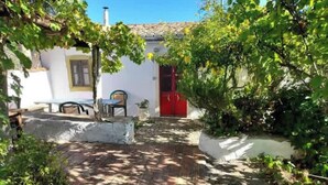 A courtyard with a white building, a red door, and a stone pathway. - Traditional Country Home (São Brás de Alportel)