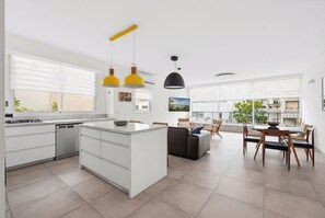 A modern kitchen with white cabinetry, a central island, and a dining area with a table and chairs. - Spacious Quiet 2BR & Parking City Center by FeelHome (Tel Aviv - Jaffa)