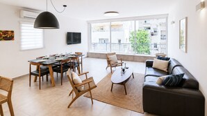 Ett modernt vardagsrum med en matplats, stora fönster och en svart lädersoffa.