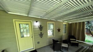 A covered porch with a yellow door, two windows, a star decoration, wicker furniture, and a concrete floor. - Spacious 1-bedroom apartment in brilliant Peachtree City (PEACHTREE CITY)