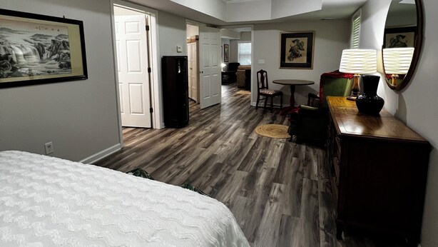 A bedroom with a bed, a dresser, a mirror, and a door leading to a bathroom. - Spacious 1-bedroom apartment in brilliant Peachtree City (PEACHTREE CITY)