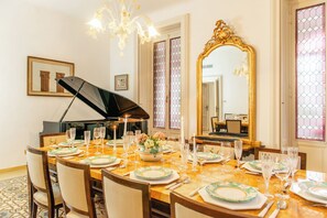 A dining room with a piano, a large mirror, and a chandelier. - Villa Evelina (Travedona-Monate)