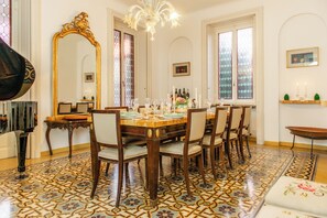 A dining room with a large ornate mirror, a chandelier, and a patterned floor. - Villa Evelina (Travedona-Monate)