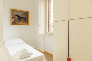 A bedroom with a bed, a white wall, a painting of a horse, and a wardrobe. - Villa Evelina (Travedona-Monate)