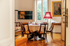 A dining room with a wooden table, chairs, and a red lamp. - Villa Evelina (Travedona-Monate)