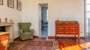 A room with a wooden dresser, a green floral armchair, a patterned rug, and framed pictures on the wall. - Villa La Limonera (Casciago)