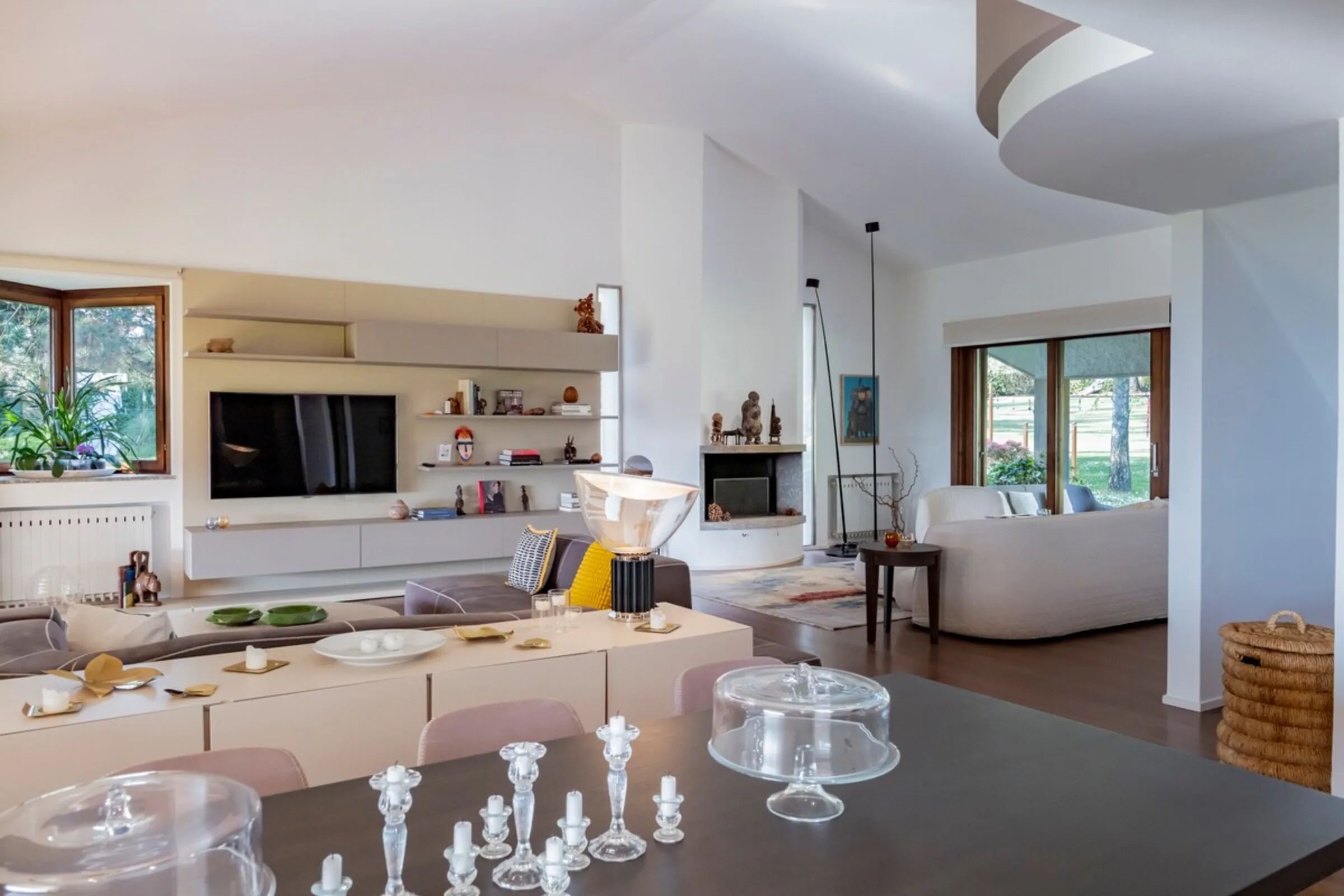 Uma sala de estar moderna com área de jantar, lareira e uma janela grande.