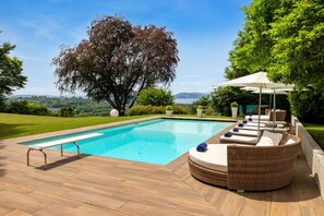 Una piscina con lettini e un gazebo, immersa nel verde con vista sul paesaggio.