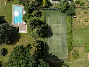An aerial view of a property with a swimming pool, tennis court, and surrounding greenery. - Villa Serenity (Besozzo)