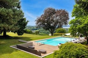 Una piscina con bordo in legno, lettini da relax e vista sul paesaggio.