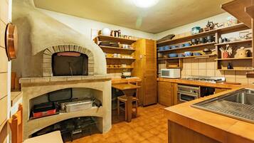 A kitchen with a built-in oven, wooden shelves, a microwave, and a sink.