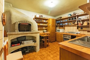 A kitchen with a built-in oven, wooden shelves, a microwave, and a sink.
