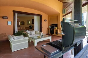 A patio area with a grill, wicker furniture, and a glass coffee table.