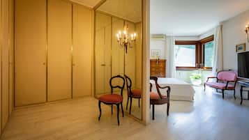A bedroom with a bed, a desk, a chair, a mirror, a wardrobe, and a window.