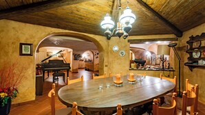 A dining area with a round wooden table, chairs, and a chandelier. - Villa La Fortezza (Dormelletto)