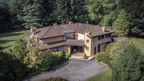 A two-story house with a tiled roof, a driveway, and a well-maintained lawn. - Villa La Fortezza (Dormelletto)