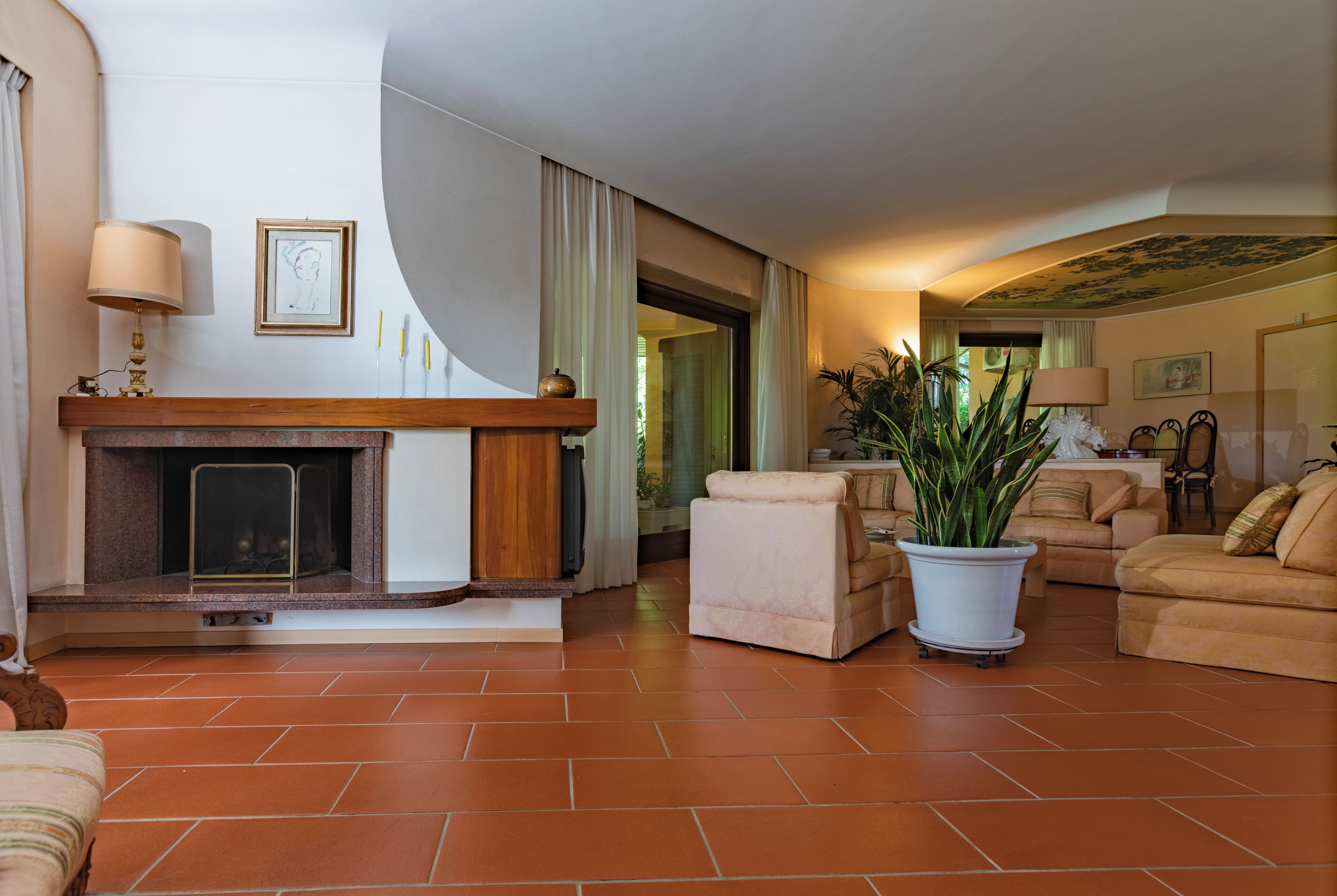 A living room with a fireplace, a sofa, a chair, and a potted plant.