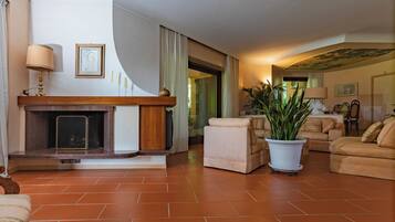 A living room with a fireplace, a sofa, a chair, and a potted plant.