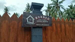 A wooden sign for Borneo Log Cabin Guest House with contact information. - Borneo Log Cabin Guest House (Tejakula)