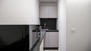 A narrow kitchen with white cabinets, a black countertop, and a stainless steel faucet. - Italianway - The B Village Standard - Apt T2 (Milan)