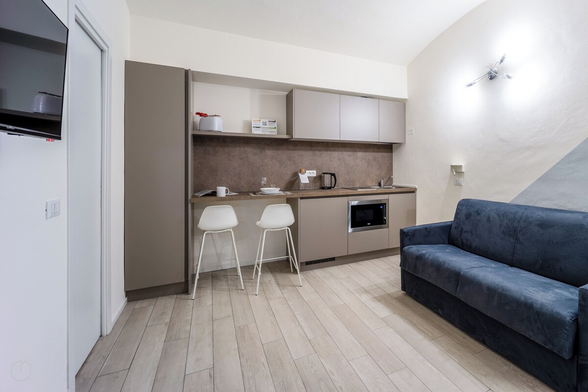 A compact living space with a kitchenette, a sofa, and a dining area.