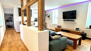 Una sala moderna con piso de madera, un sofá, una mesita de centro y un televisor montado en la pared.