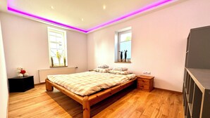 Un dormitorio con una cama de madera, mesitas de noche, una ventana y un radiador.