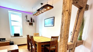 Un comedor con una mesa y sillas de madera, una ventana con persianas y un radiador.