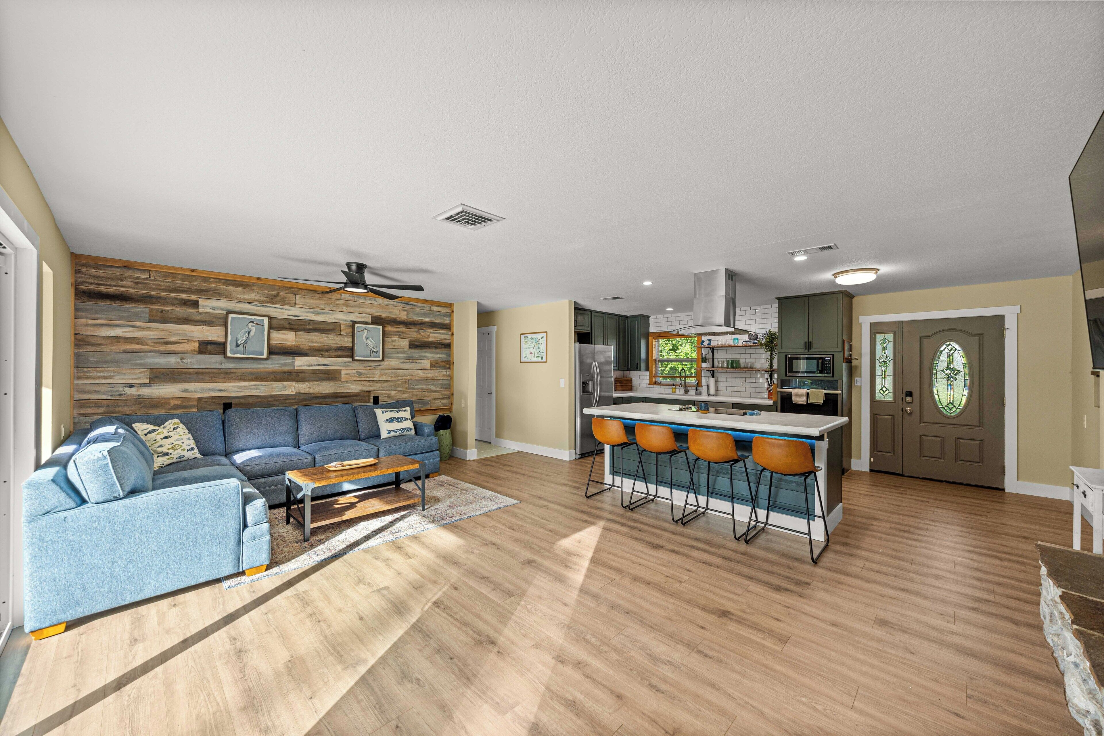 Un salon moderne avec un canapé bleu, un lambris en bois et un ventilateur de plafond.