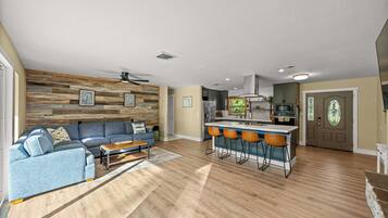 Un salon moderne avec un canapé bleu, un lambris en bois et un ventilateur de plafond.