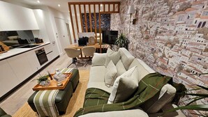 A modern living room with a sofa, coffee table, and a kitchen area in the background. - Modern Studio Greater London (New Malden)