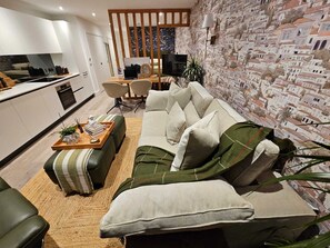 Ein modernes Wohnzimmer mit einer Couch, einem Couchtisch und einer Küchenzeile im Hintergrund.