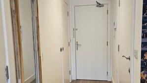 A hallway with wooden flooring, white doors, and a ceiling light fixture. - Modern Studio Greater London (New Malden)