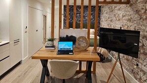 A modern kitchen with a wooden dining table, a laptop, a TV, and a cityscape wallpaper. - Modern Studio Greater London (New Malden)
