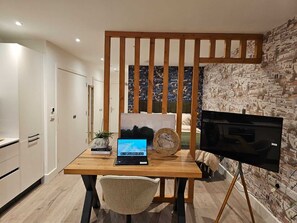 Eine moderne Küche mit einem Holztisch, einem Laptop, einem Fernseher und Stadthaussicht-Tapete.