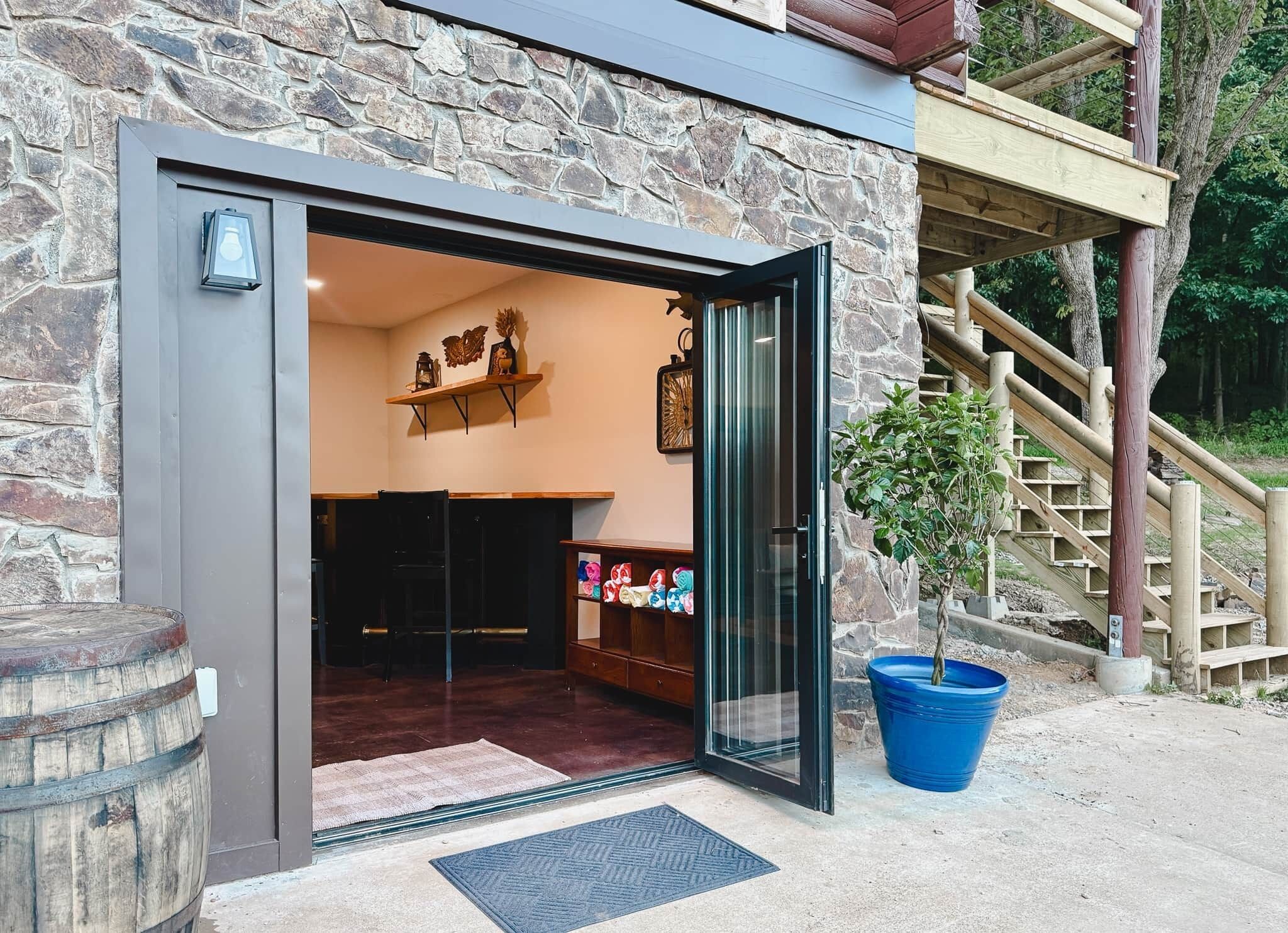A stone building entrance with a glass door, a wooden staircase, and a potted plant.