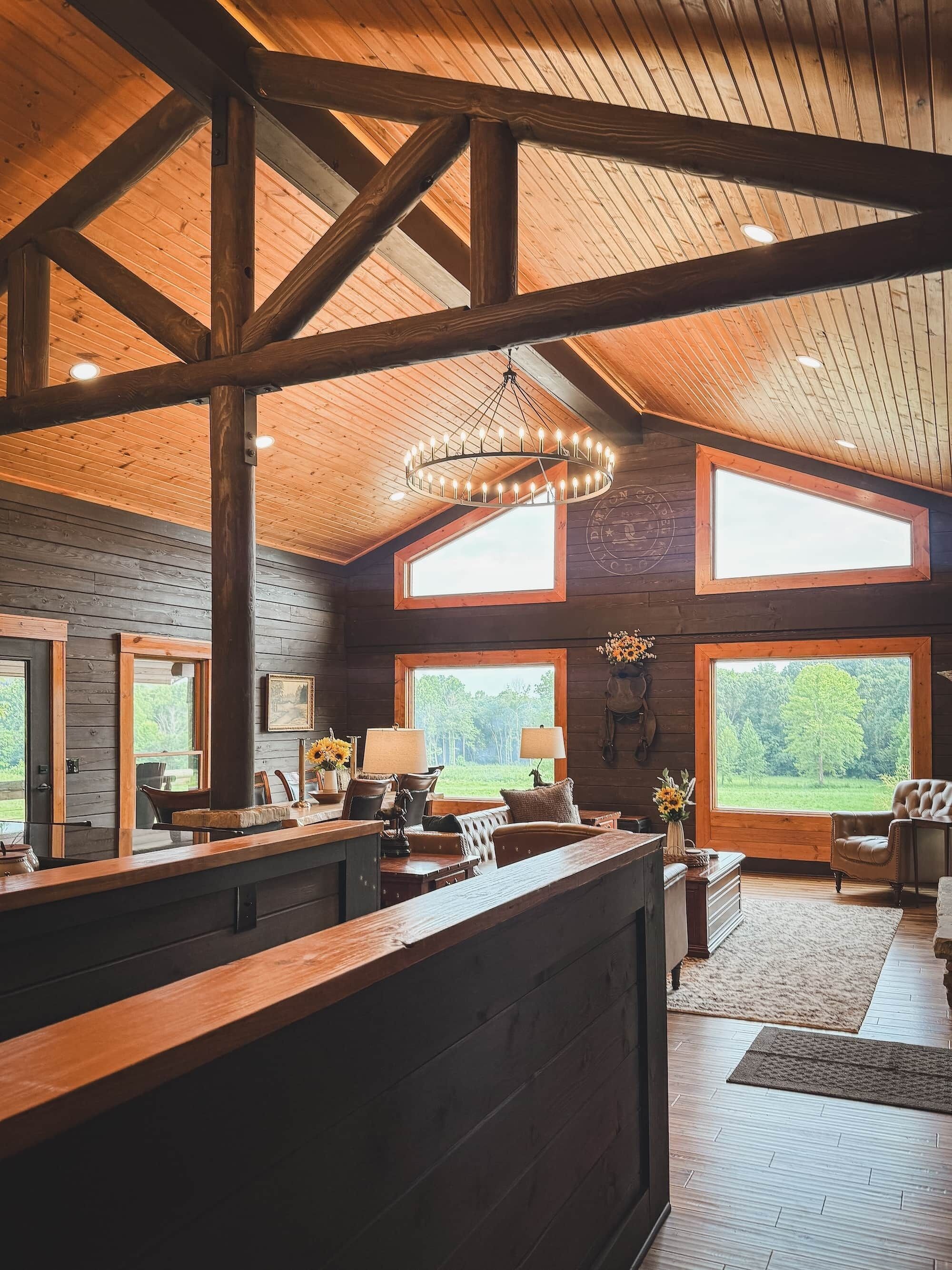 A spacious room with a wooden ceiling, large windows, and a central chandelier.
